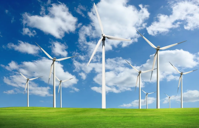 An image of windmills on grass with a partly cloudy sky background
